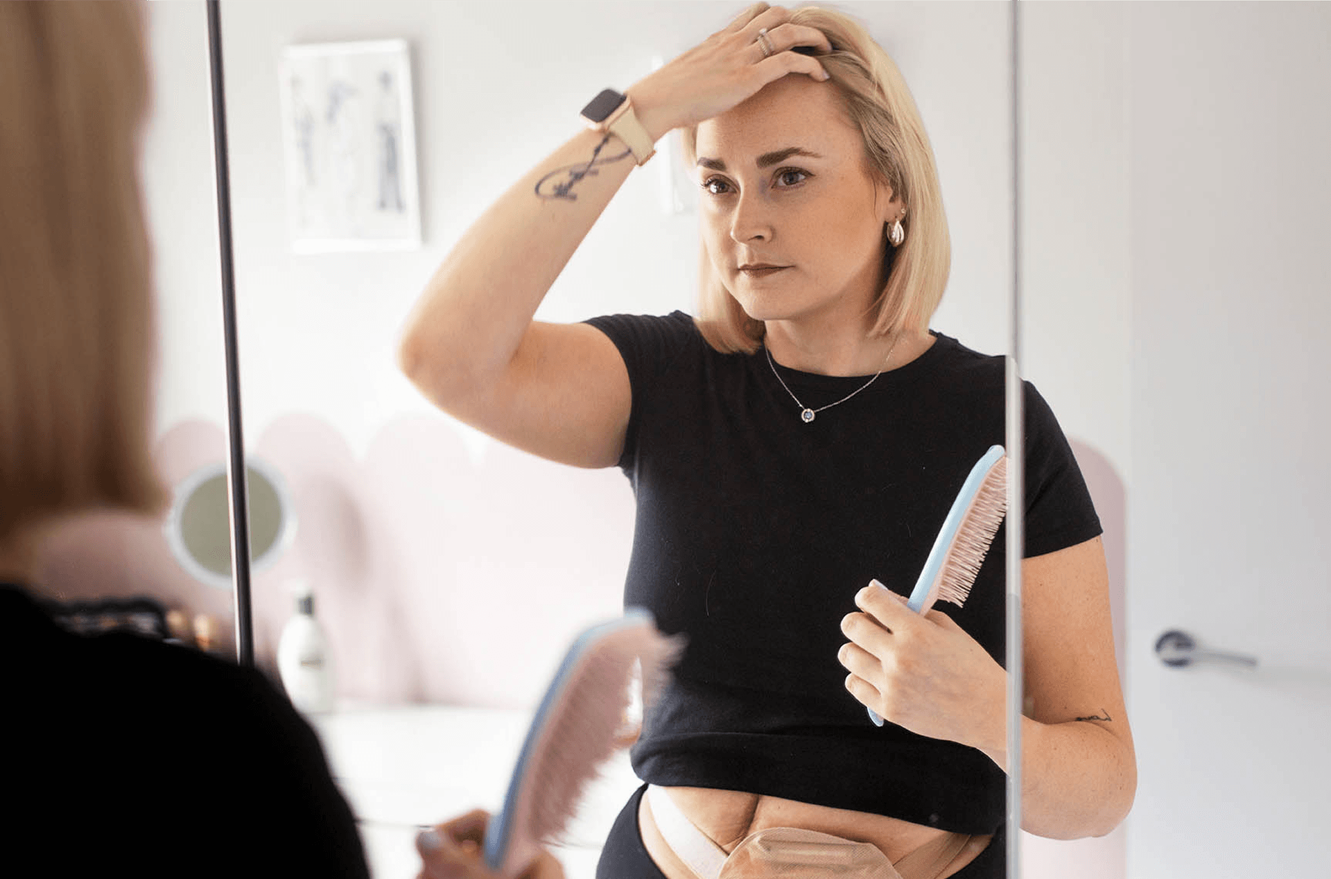 Frau mit Stoma kämmt sich vor dem Spiegel