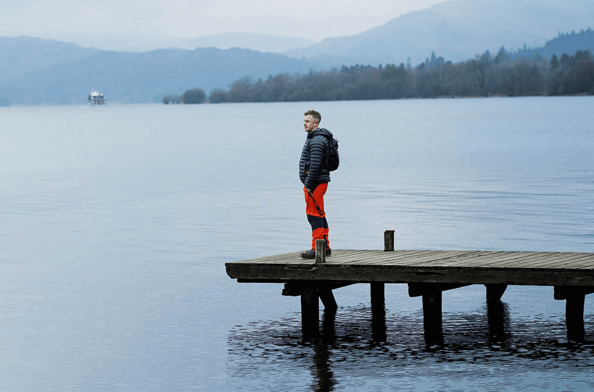 Mann steht auf einem Steg an einem See